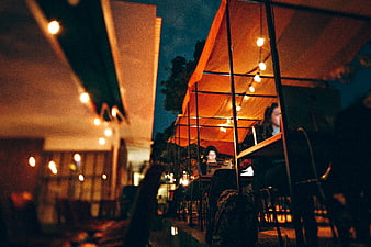 Woman working on laptop at outdoor cafe at night