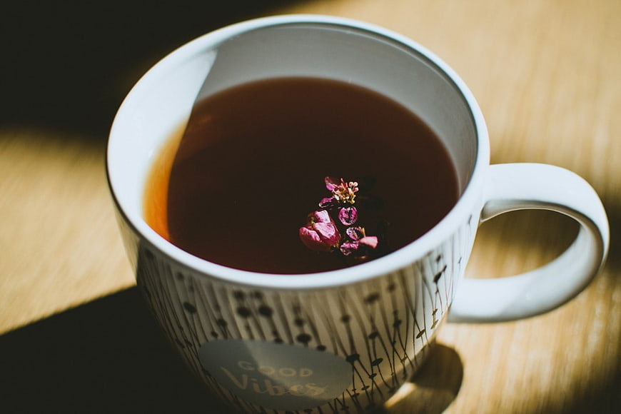 White Mug of Herbal Tea with Dried Flowers on Wooden Table