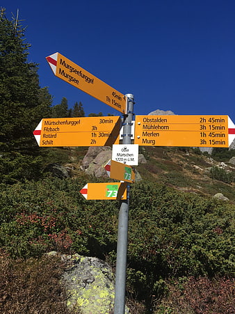 Alpine hiking signpost with trail directions and times