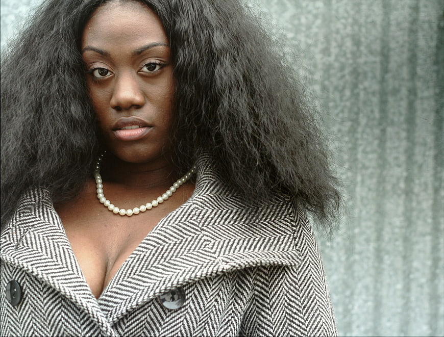 Portrait of stylish woman with afro hair and herringbone coat