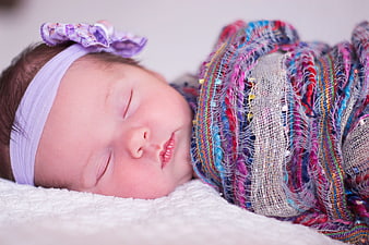Sleeping newborn baby girl wrapped in colorful knit blanket