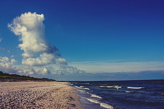 Sandy Beach with Dramatic Clouds and Blue Ocean Waves