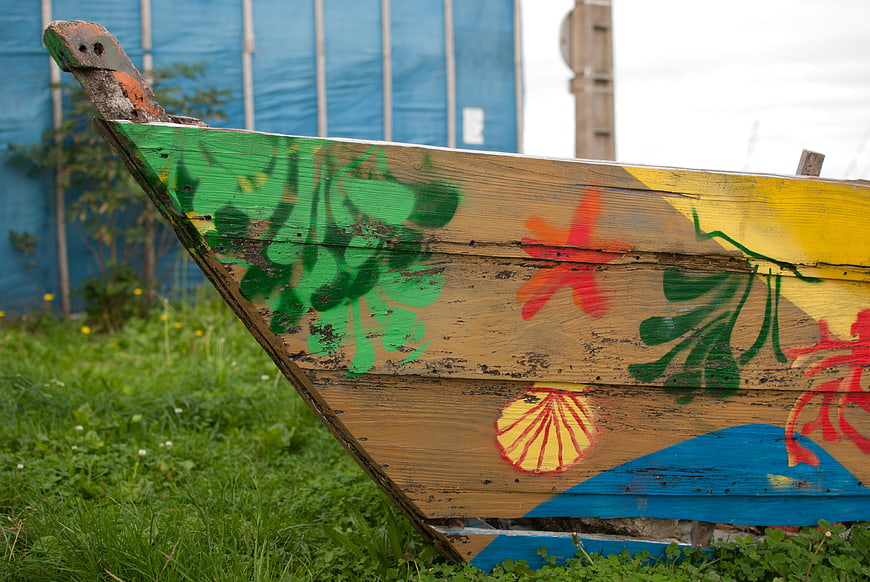 Close-up of weathered wooden boat with colorful painted sea motifs