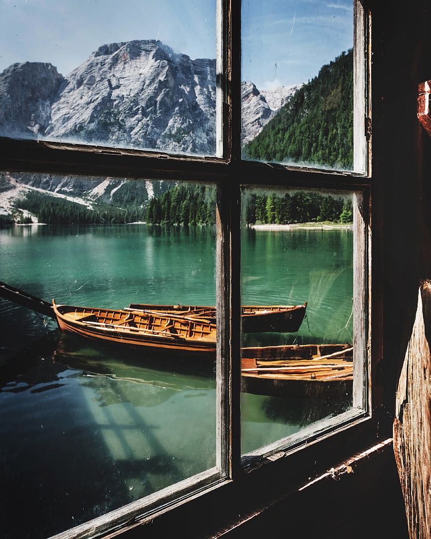 Wooden boats on turquoise lake seen through rustic window