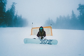 Snowboarder sitting in foggy winter forest