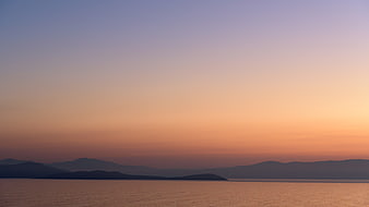 Serene Sunset Over Ocean with Mountain Silhouettes