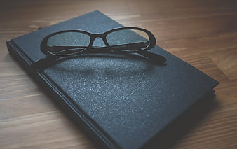 Black Eyeglasses on Textured Notebook on Wooden Table