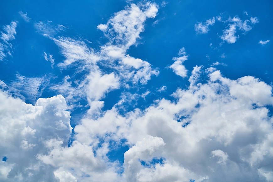Fluffy white clouds against a vibrant blue sky background