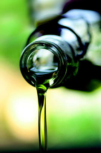 Close-up of olive oil pouring from a glass bottle