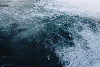 Aerial view of turbulent dark ocean waves and white foam