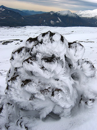 Frost-covered rock formation in snowy mountain landscape