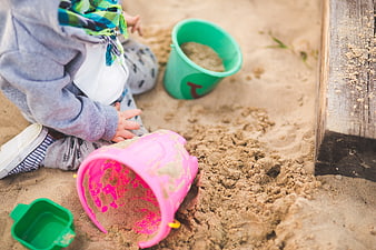 Child playing with colorful buckets in a sandbox