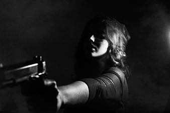 Dramatic black and white portrait of woman aiming pistol