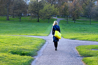 Woman with Yellow Bag Walking on Park Path