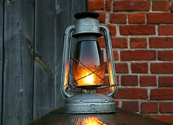 Vintage Kerosene Lantern with Warm Flame on Wooden Surface
