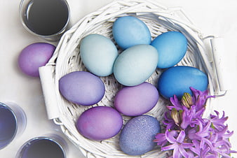 Blue and purple Easter eggs in white basket with hyacinths