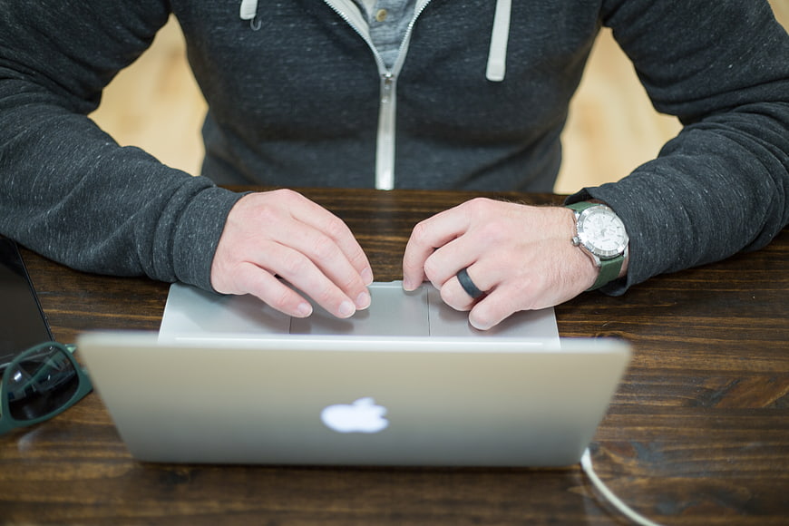 Man Typing on Laptop at Wooden Desk