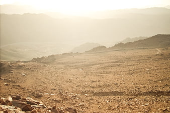 Sunny arid mountain landscape with rocky terrain and hazy valley
