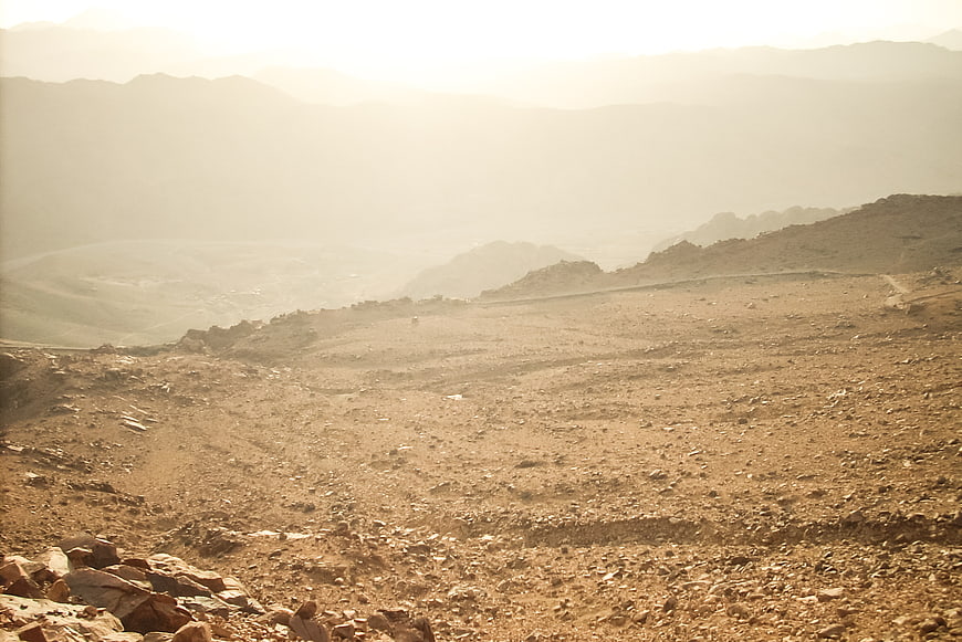 Sunny arid mountain landscape with rocky terrain and hazy valley