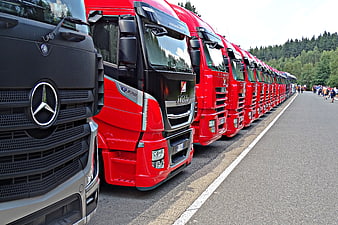 Line of red and black semi-trucks parked on road