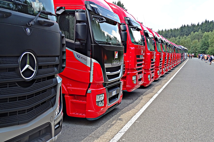 Line of red and black semi-trucks parked on road