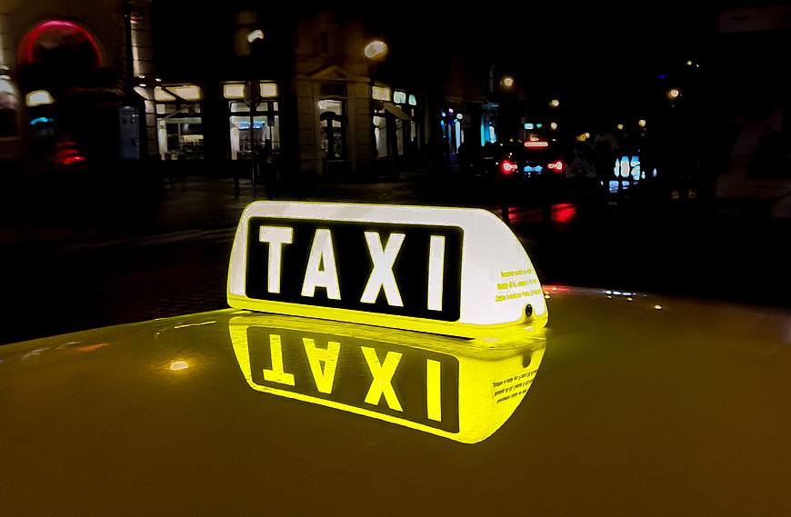Illuminated Taxi Sign on Yellow Car Roof at Night