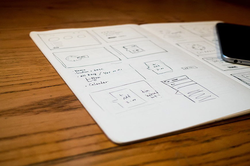 Hand-drawn mobile app wireframe sketches on notebook