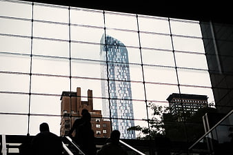 Silhouetted commuters on stairs against modern glass skyscraper