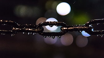 Close-up of wet metal chain with bokeh lights