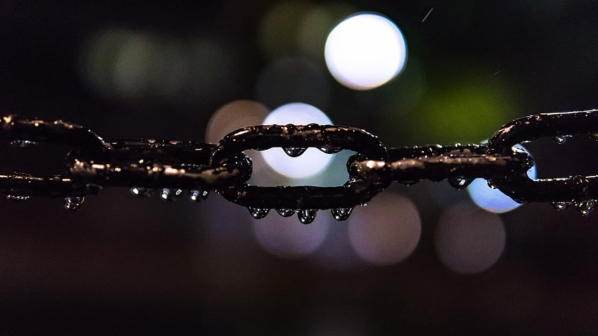 Close-up of wet metal chain with bokeh lights