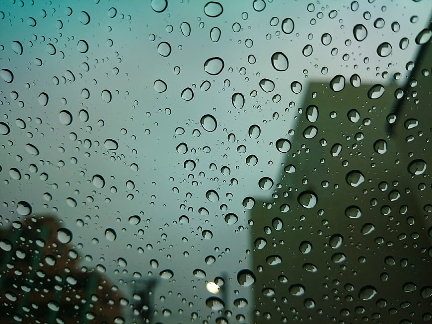 Raindrops on Window Glass with Blurred City Background