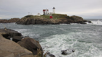 Coastal Lighthouse On Rocky Island With Churning Ocean Waves