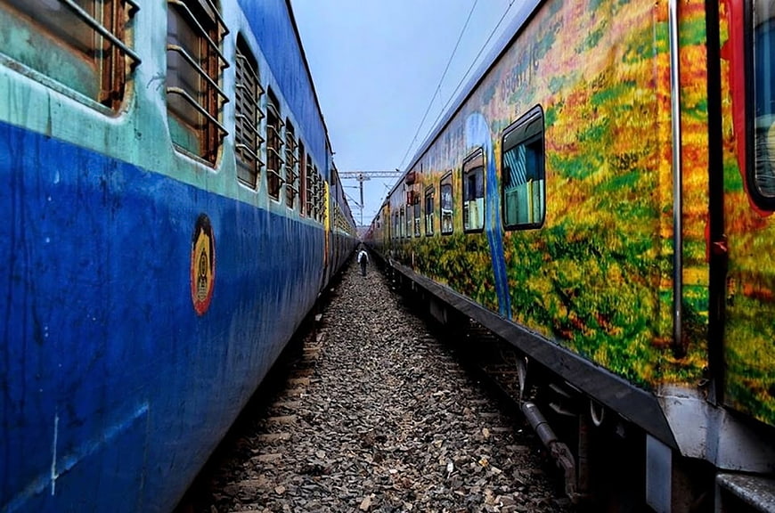 Two Indian passenger trains parked side-by-side on railway tracks