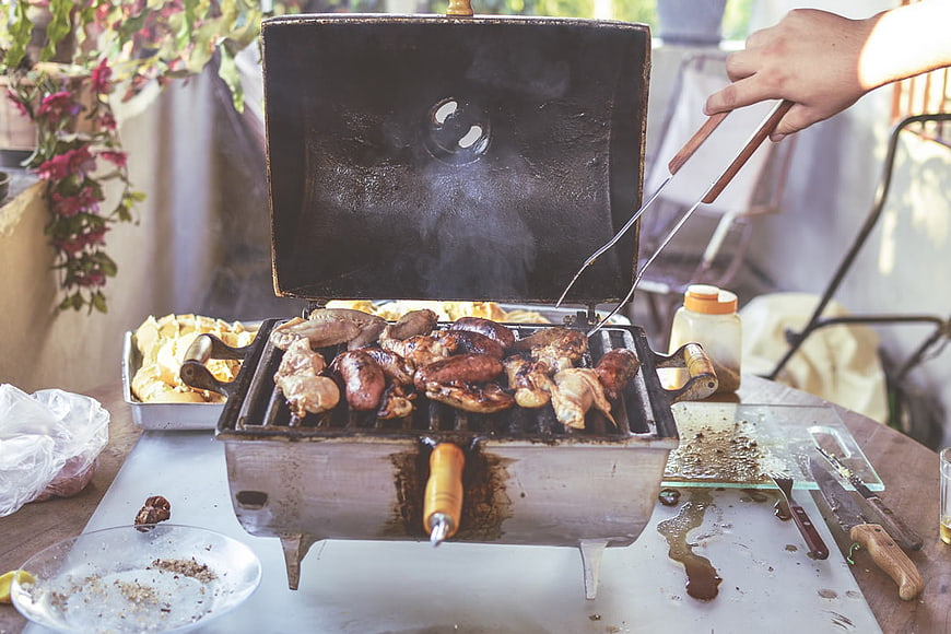 Grilling Chicken and Sausages on Outdoor Barbecue