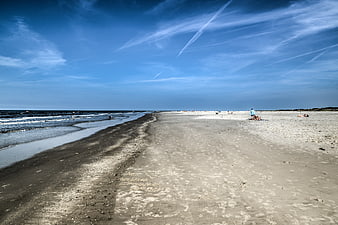 Wide sandy beach with blue sky and ocean waves