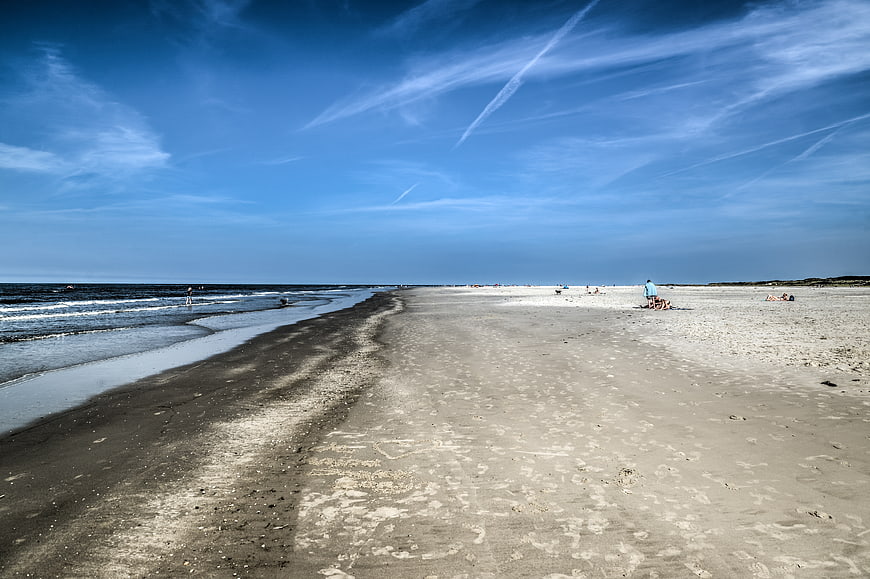 Wide sandy beach with blue sky and ocean waves