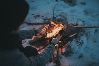 Woman Warming Hands By Snowy Campfire In Winter Forest