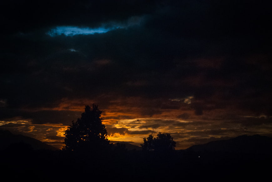 Dramatic sunset silhouette with dark clouds and golden horizon