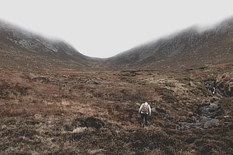 Lone Hiker Walking Through Misty Mountain Valley
