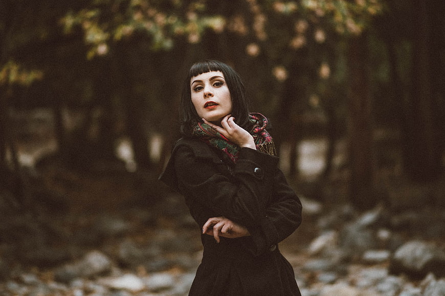 Woman in black coat and scarf in autumn forest