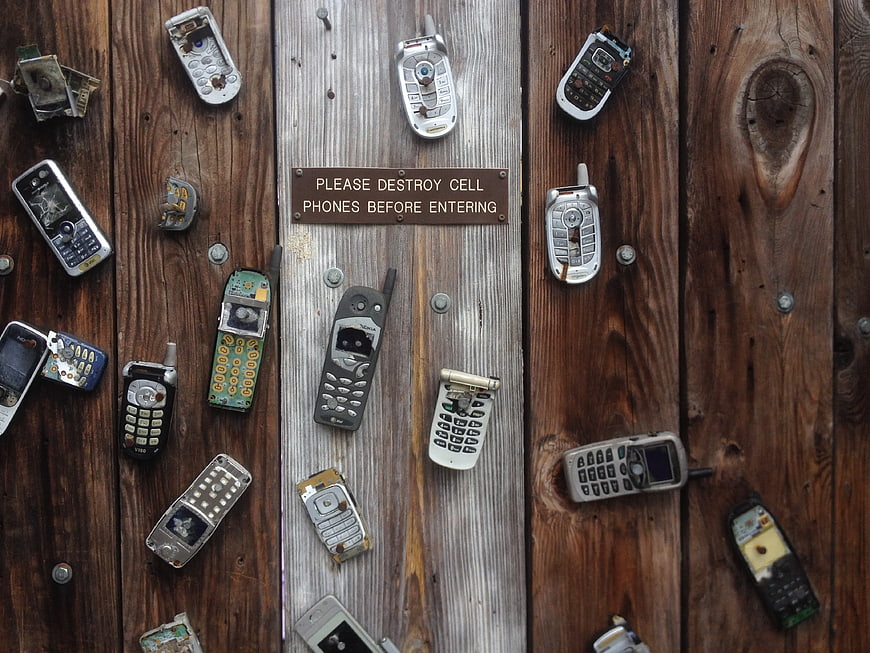 Broken vintage cell phones on wooden planks with sign