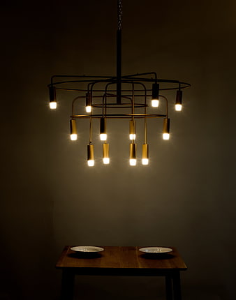 Modern Brass Chandelier With Warm LED Bulbs Over Wooden Dining Table