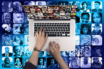 Hands typing on laptop with diverse faces background