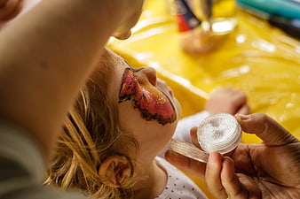 Child getting butterfly face paint with glitter