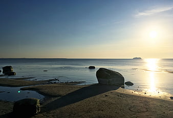 Serene Beach Sunset with Rocks and Distant Ship