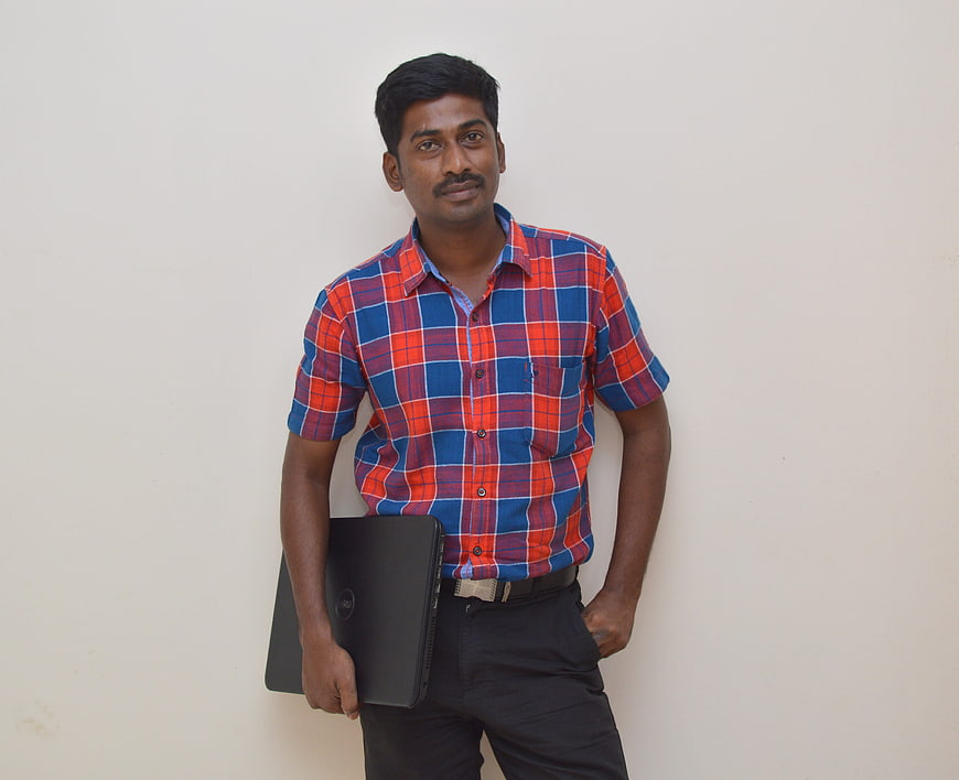 Indian man holding laptop against white wall