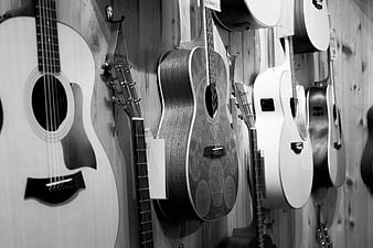 Black and white acoustic guitars hanging on wooden wall