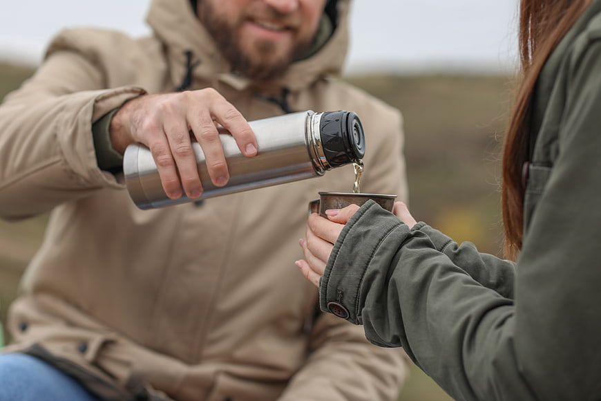 Couple Pouring Hot Drink from Thermos Outdoors