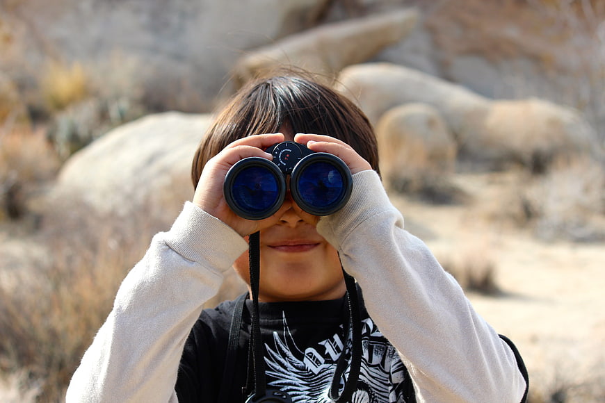 Child Looking Through Binoculars in Desert Landscape