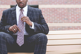 Man in Plaid Suit Adjusting Tie on Bench